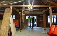 Takmøne, vinduer og vinnehjul sett innenfra i Kjøpmannsgata 15 i Trondheim under oppussing. Bygningsmaterialer på gulvet. Ståle og Trond Are kommer inn fra stillaset.