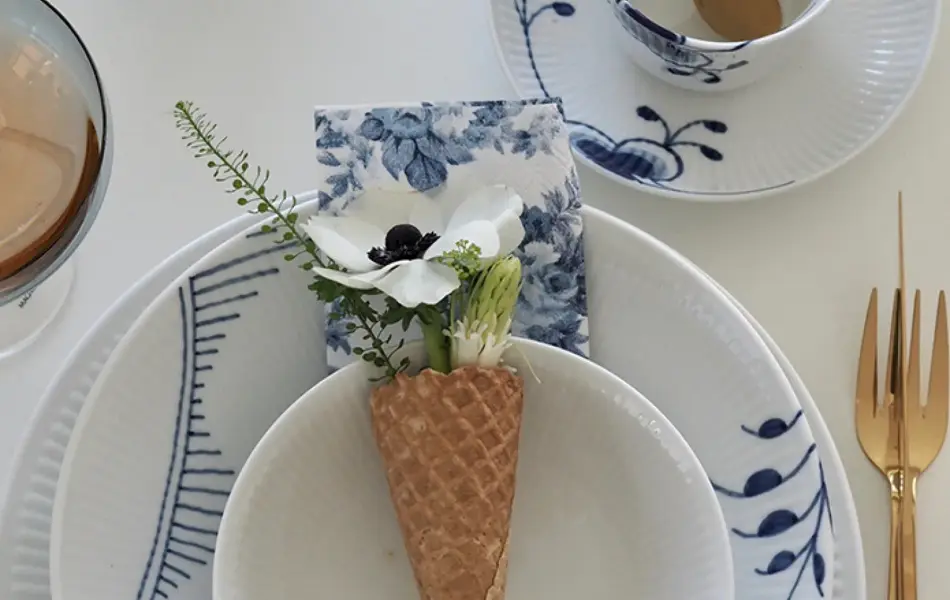 Kuvert med hvitt servise med blått mønster, iskremkjeks med blomster i brukt som dekor.