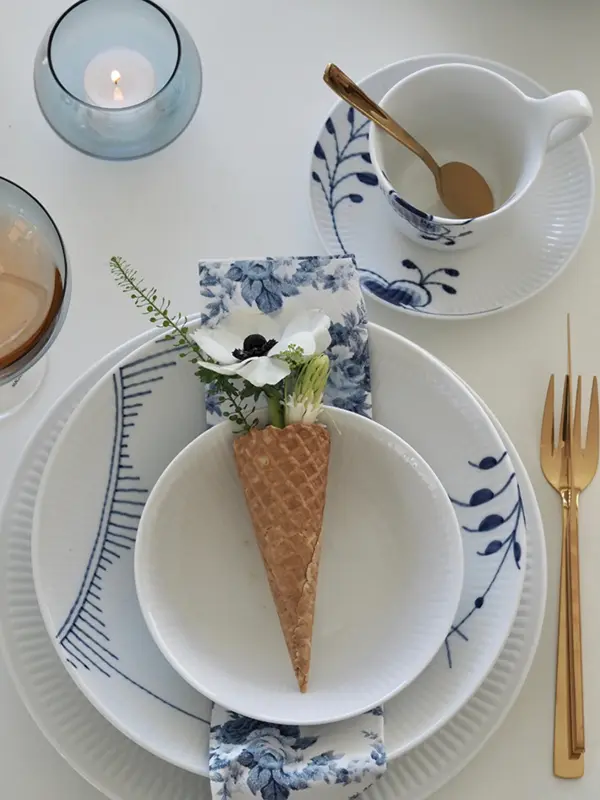 Kuvert med hvitt servise med blått mønster, iskremkjeks med blomster i brukt som dekor.