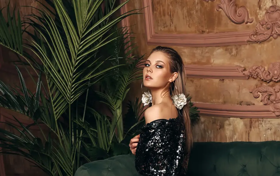 Modell poserer med svart paljettkjole i en grønn sofa