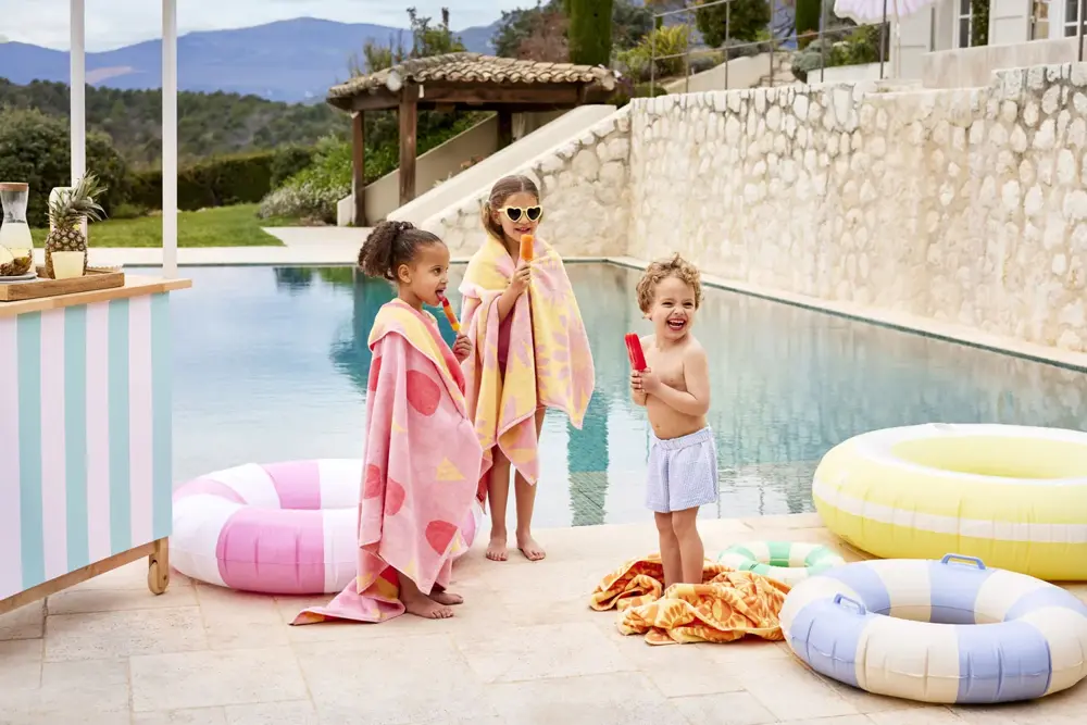 Barn med badeponcho som står ved bassengkanten