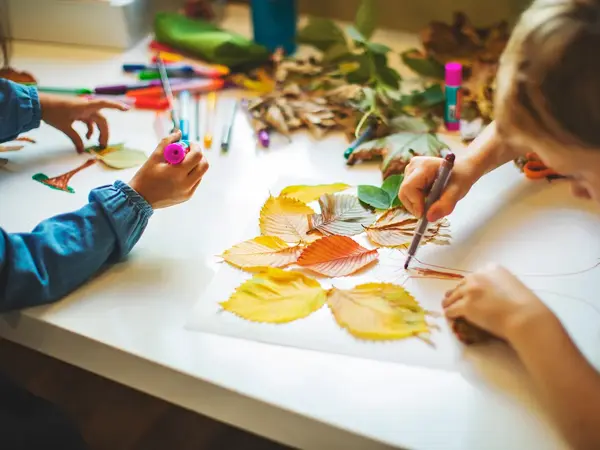 Barn lager bilde med høstblader. Foto.