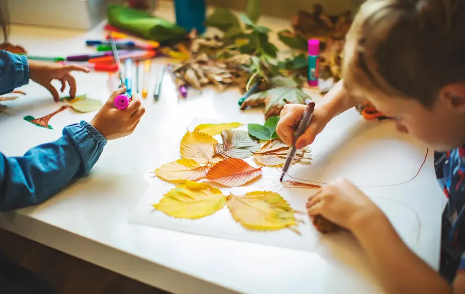 Barn lager bilde med høstblader. Foto.
