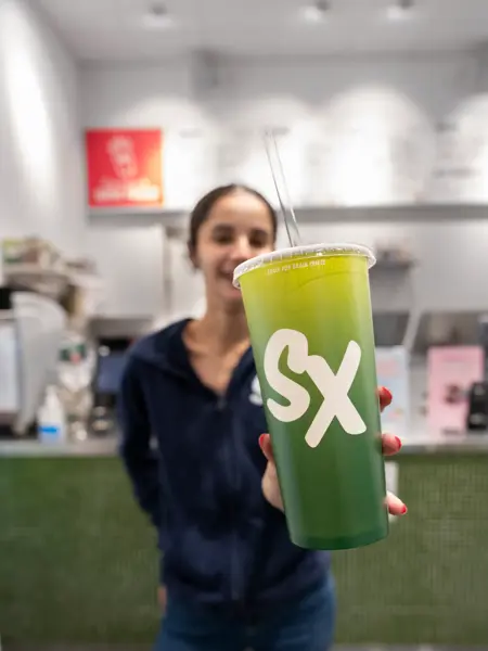 Jente som holder frem et beger med Smoothie fra SmoothieXchange 
