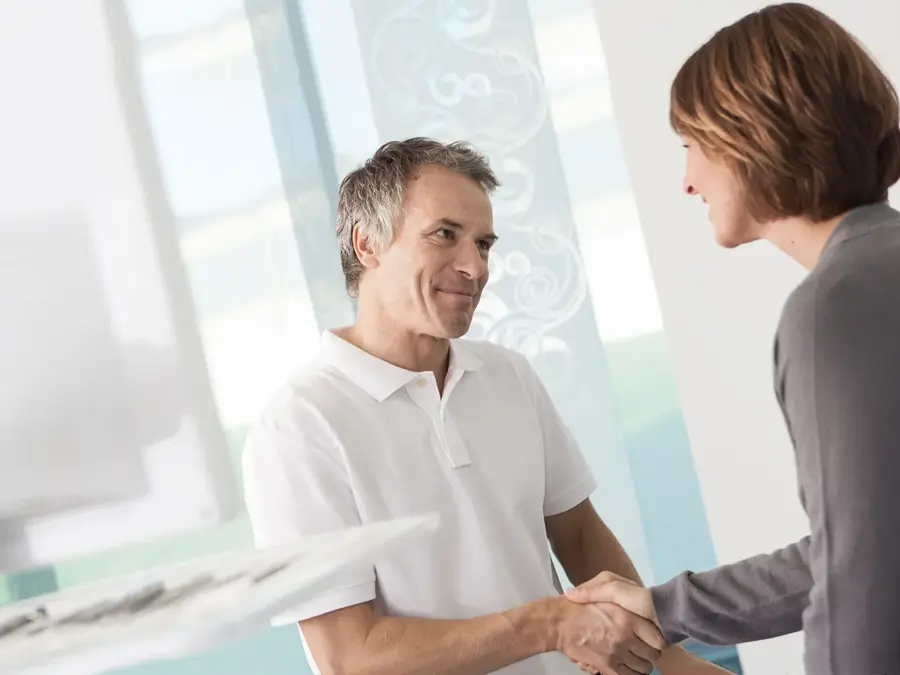 Mann i hvit skjorte som tar dame med grå genser i hånden