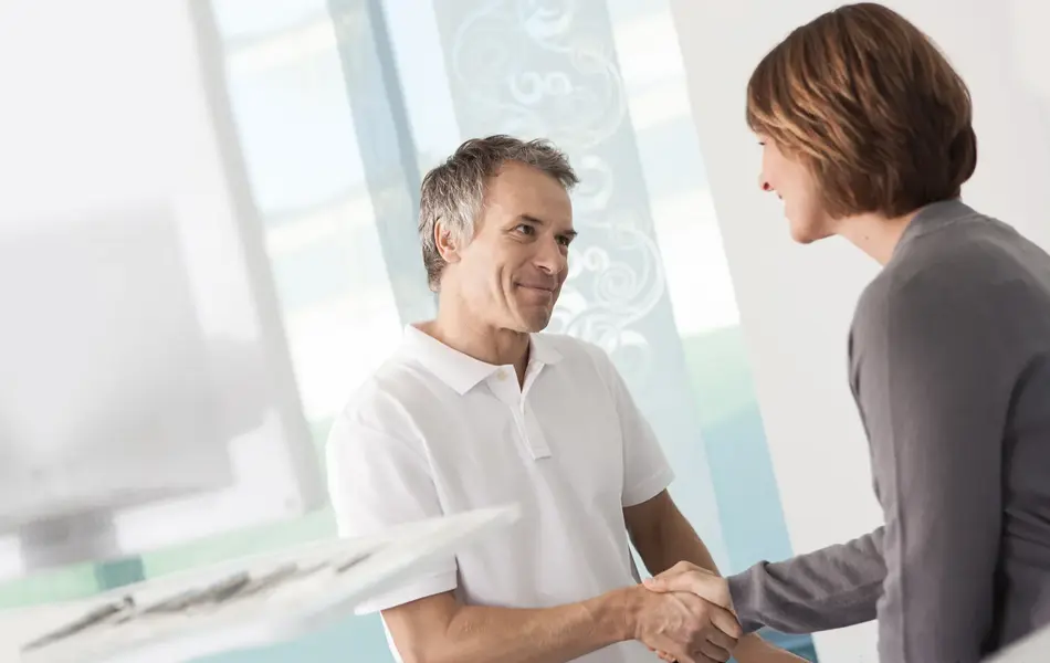 Mann i hvit skjorte som tar dame med grå genser i hånden