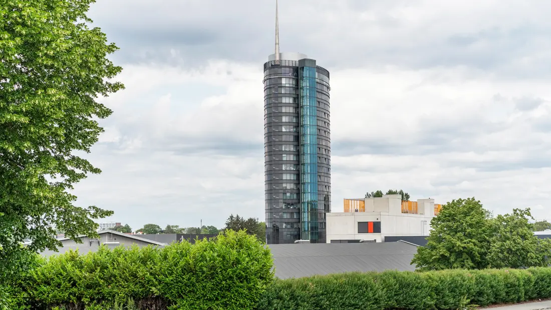 Fasaden til Thon Partner Stavanger Forum Hotel. Bygning, med 21 etasjer, med antenne på toppen. Grønne hekker og trær rundt. Himmel med grå skyer.