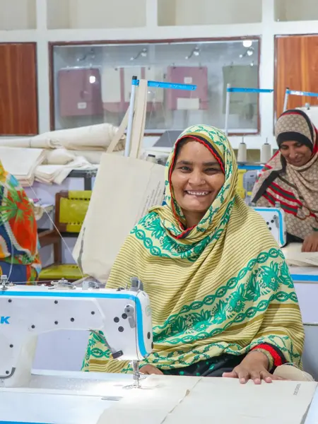 Dame som smiler og syr et handlenett