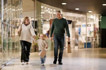En mann, en kvinne og en liten jente går bortover en gang i et kjøpesenter