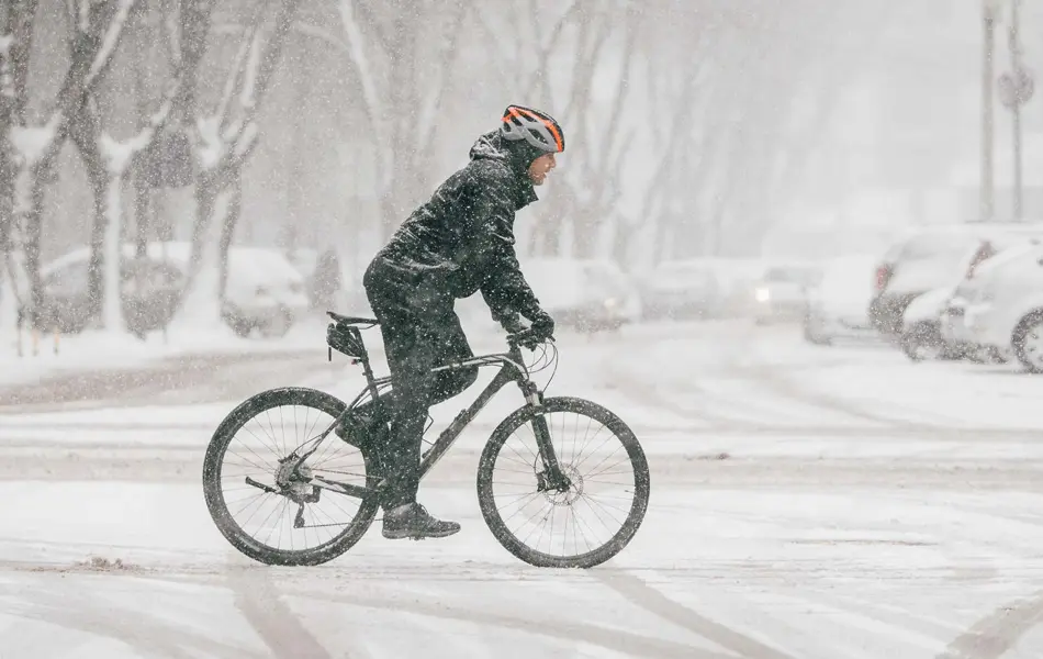 Person på sykkel i urbant snølandskap