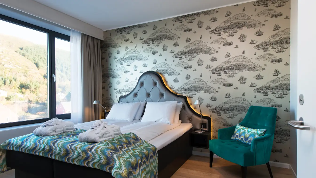 Dobbelseng og stol i suite på Thon Hotel Fosnavåg med utsikt utover havet