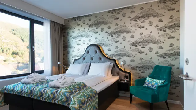 Dobbelseng og stol i suite på Thon Hotel Fosnavåg med utsikt utover havet