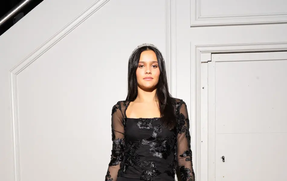 Dame i svart topp, bukse og glitrende veske