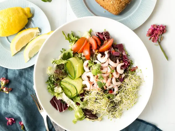 Blandet salat, rundstykke og sitron på fat 