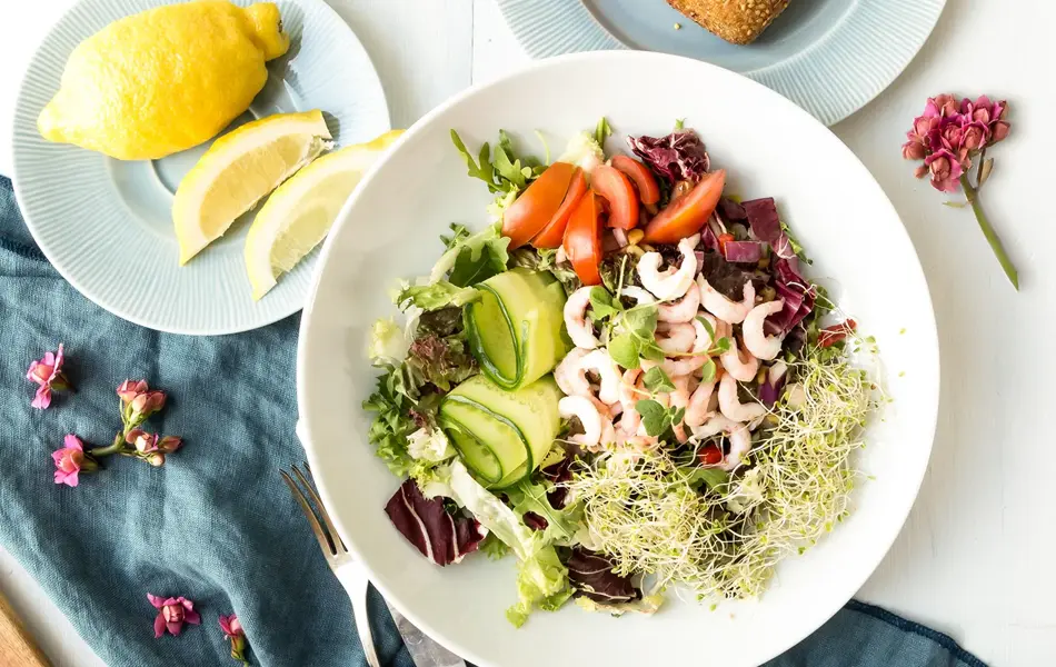 Blandet salat, rundstykke og sitron på fat 