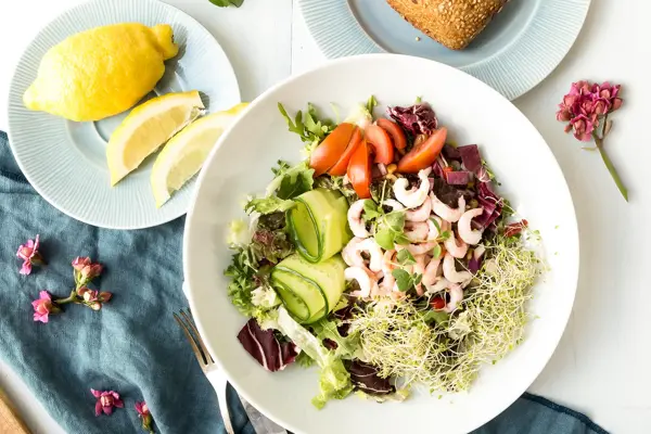 Blandet salat, rundstykke og sitron på fat 