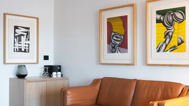 Brun skinnsofa på suite, og bilder på veggene