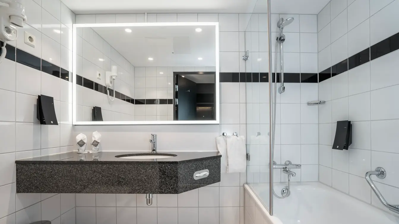 Hvite gulv og veggfliser, badekar med dusj, speil, vask