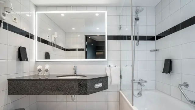 Hvite gulv og veggfliser, badekar med dusj, speil, vask