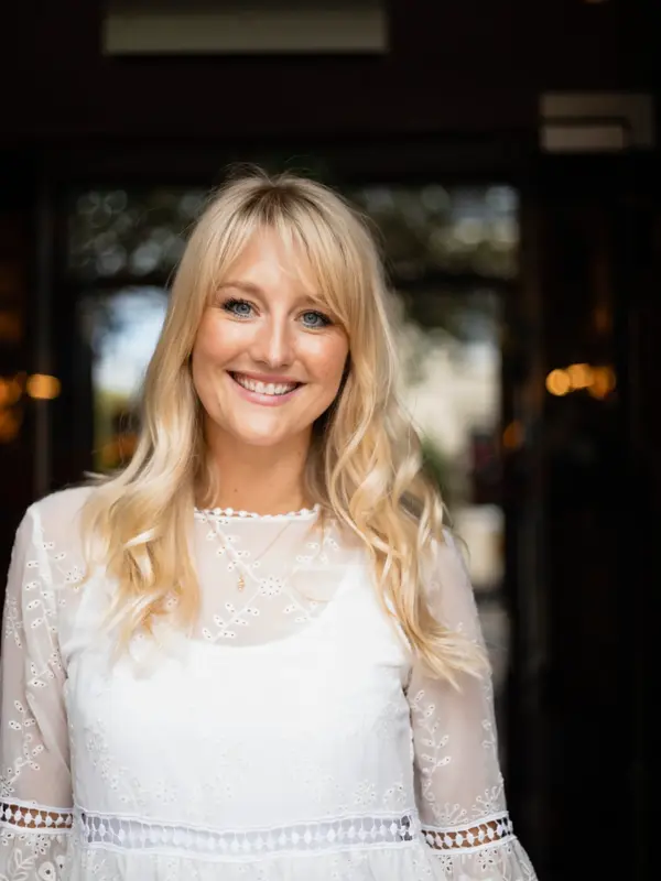 A portrait of a mid adult woman with blonde hair, smiling while looking at the camera.