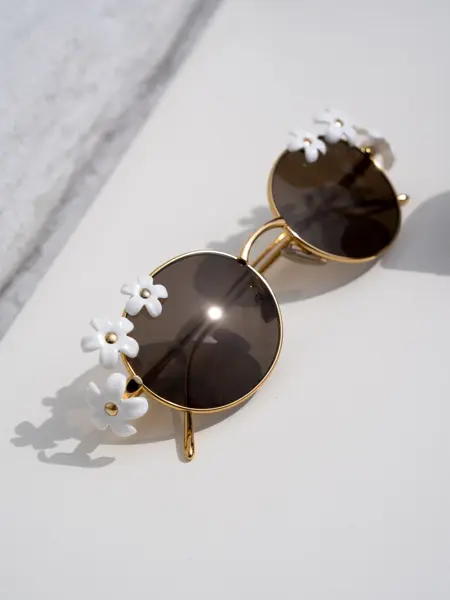 Runde solbriller med hvite blomster på siden
