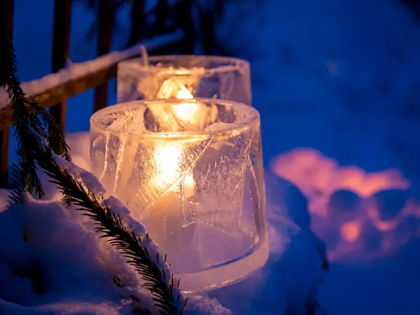 Candles placed inside the ice and snow, emitting beuatiful orange glow in darkening evening.