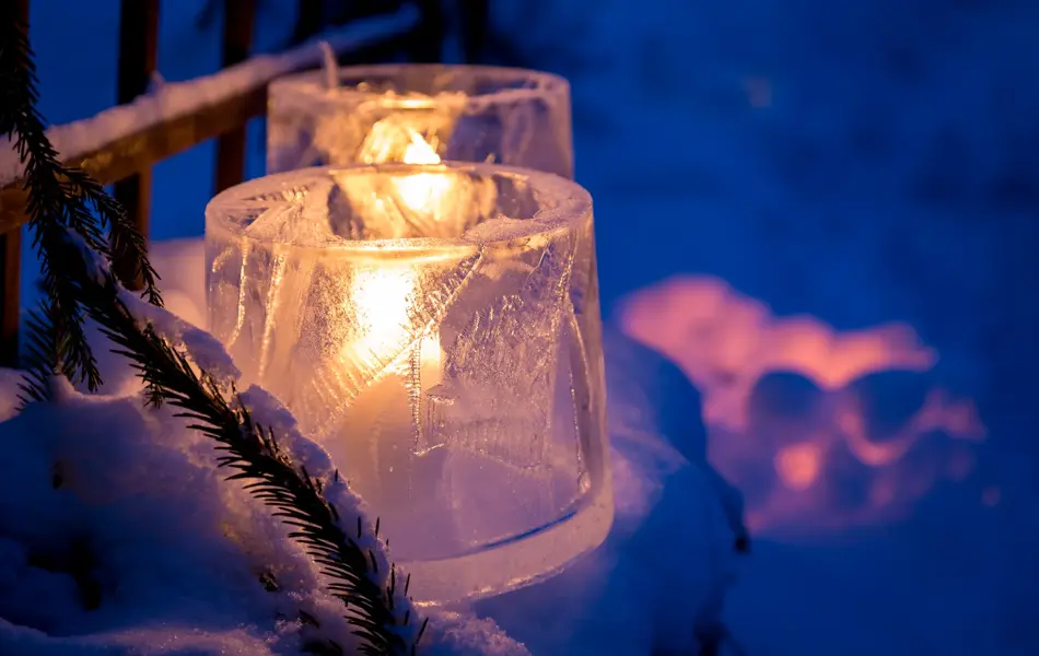 Candles placed inside the ice and snow, emitting beuatiful orange glow in darkening evening.