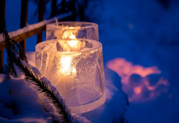 Candles placed inside the ice and snow, emitting beuatiful orange glow in darkening evening.