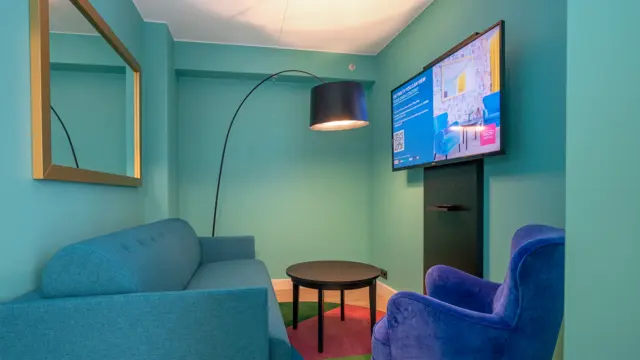 Sittegruppe med turkis sofa og blå stol og smart TV i business rom på Thon Hotel Storo