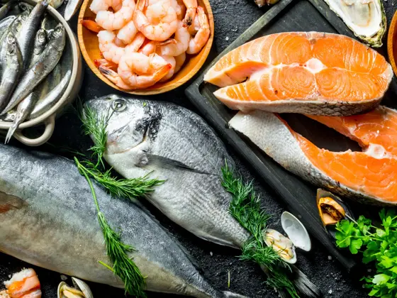 Fresh salmon steak with a variety of seafood and herbs. On black rustic background