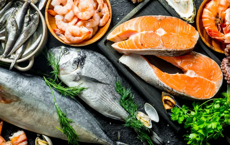 Fresh salmon steak with a variety of seafood and herbs. On black rustic background