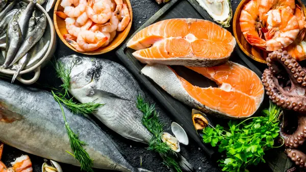 Fresh salmon steak with a variety of seafood and herbs. On black rustic background