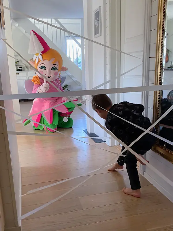 Barn som går igjennom en hinderløype laget av maskeringsteip, mens Amfelia-maskot venter ved mållinjen