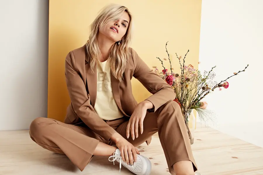 Dame sitter på gulvet ved siden av blomster