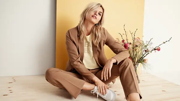 Dame sitter på gulvet ved siden av blomster