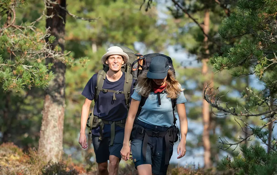 En dame og en mann på tur med sekk i skogen
