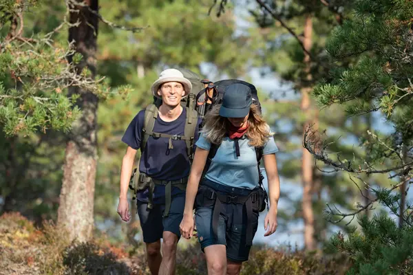 En dame og en mann på tur med sekk i skogen