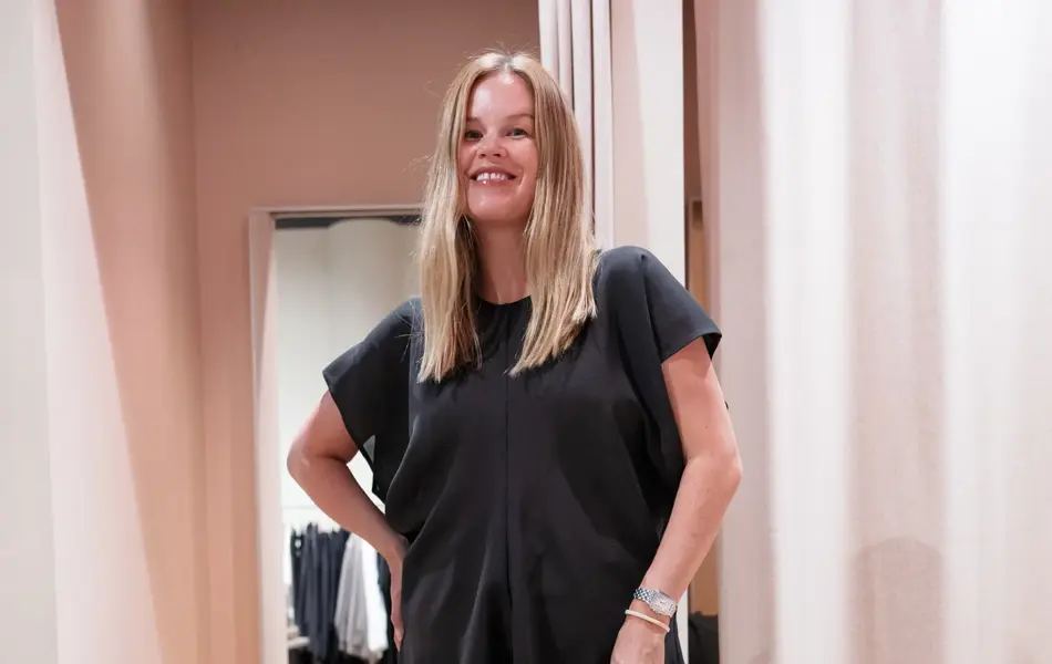 Damemodell med sort topp og sort langt skjørt og rosa veske.