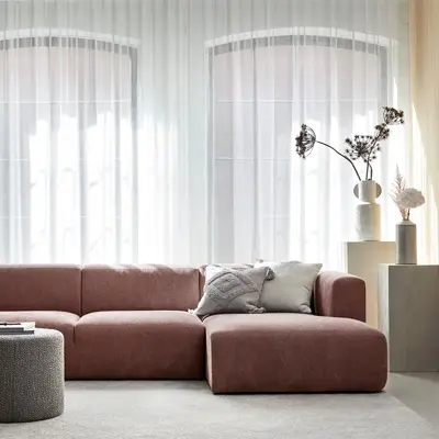 Stue med store vinduer og en rødlig sofa