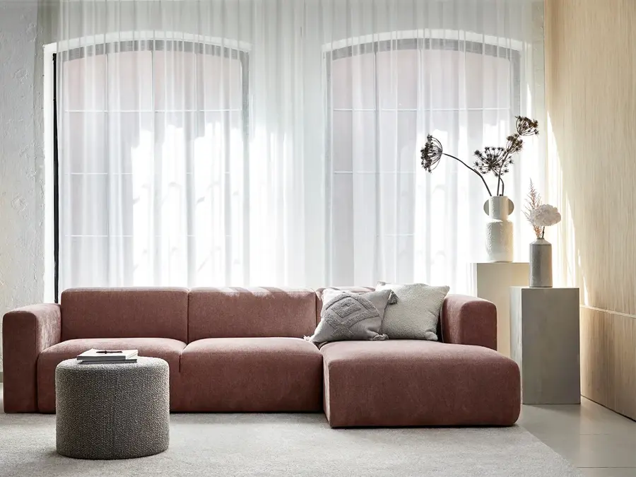 Stue med store vinduer og en rødlig sofa