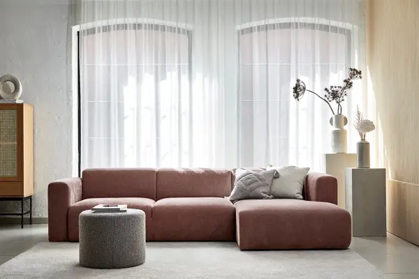 Stue med store vinduer og en rødlig sofa