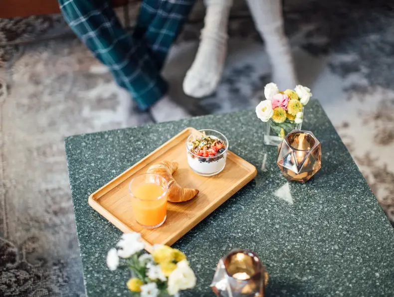 Marmorbord med trefat med en croissant, appelsinjuice og blomster