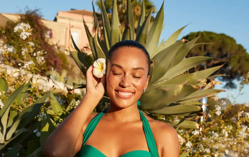 Modell ute foran grønne planter i en grønn bikini.
