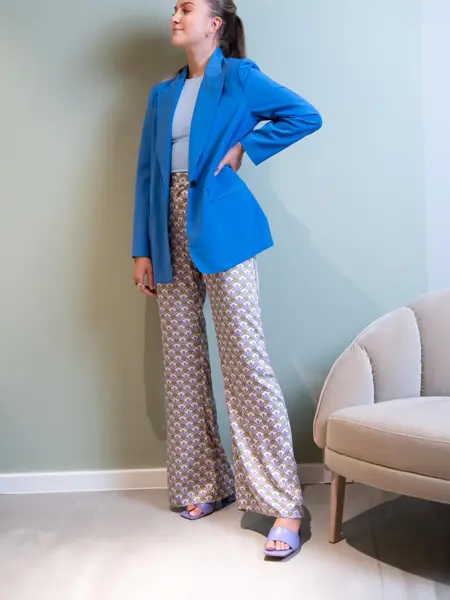 Ung kvinne som poserer i blå dressjakke og beige slengbukser