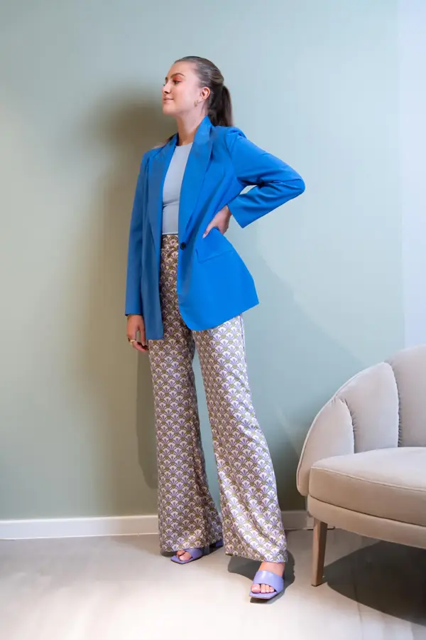 Ung kvinne som poserer i blå dressjakke og beige slengbukser