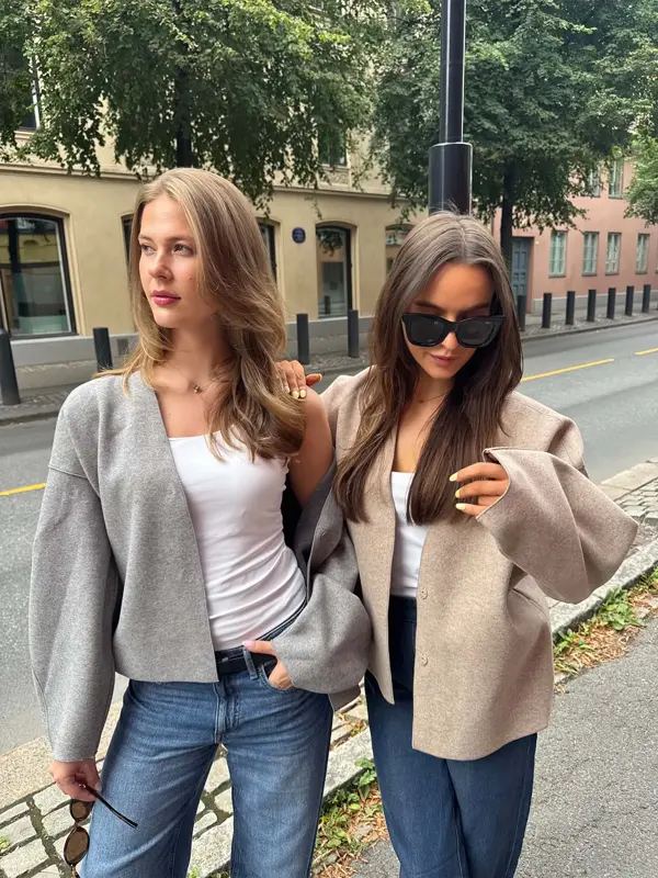 dame i grå genser, hvit skjorte og jeans, og dame i brun jakke, hvit skjorte og jeans
