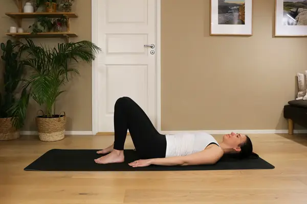 Anna viser Pilates-øvelser på treningsmatte på gulvet