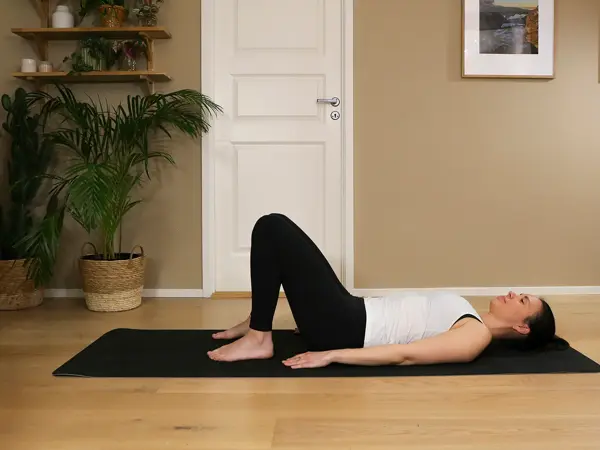 Anna viser Pilates-øvelser på treningsmatte på gulvet