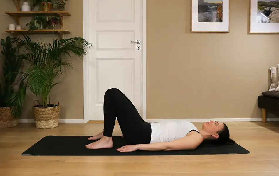 Anna viser Pilates-øvelser på treningsmatte på gulvet