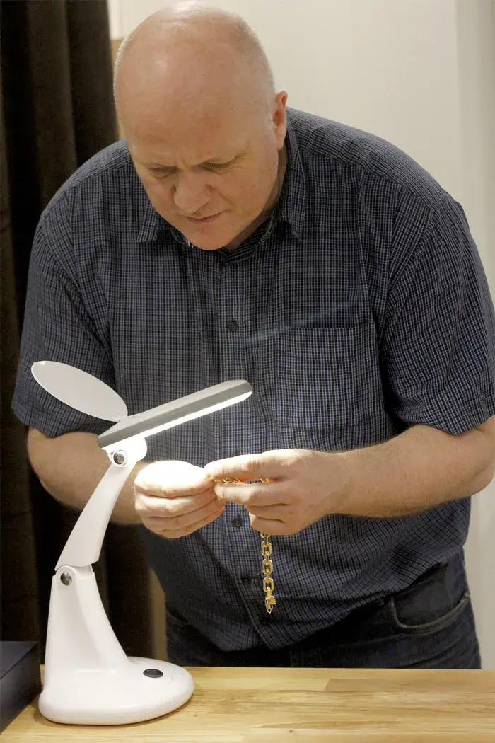 Mann som undersøker gullsmykke